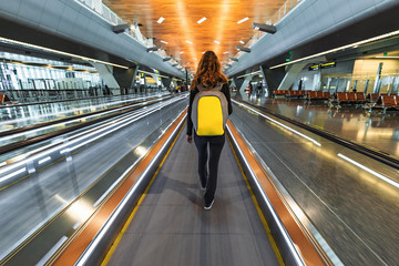 One woman traveller with backpack go on moving walkway travolator in new Hamad International...