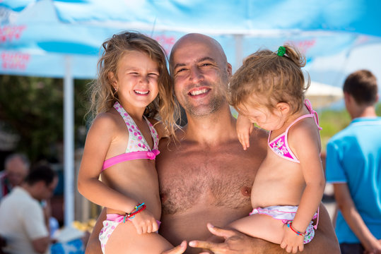 portrait of young happy father with daughters by the sea