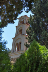 The bell tower of the church next to the tree.