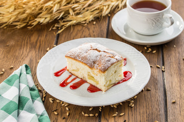 Homemade sponge cake with jam and cup of tea on wooden table