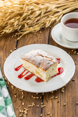 Homemade sponge cake with jam and cup of tea on wooden table