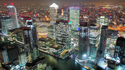 Aerial drone night shot from iconic Canary Wharf illuminated skyscrapers business and financial...