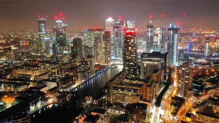 Aerial drone night shot from iconic Canary Wharf illuminated skyscrapers business and financial...