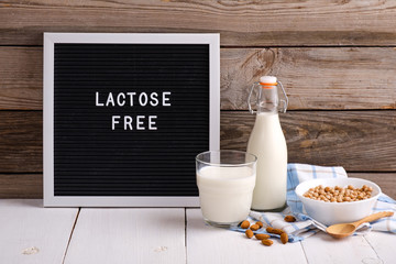 Allergic food concept. Almond milk in bottle and glass, bowl with almonds scattered around and...