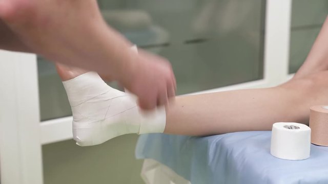 A side view of a professional therapist straddling taped with sport tape ankle. Therapy and rehabilitation concept