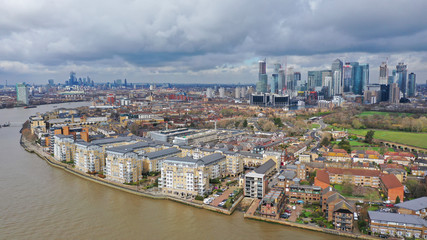 Naklejka premium Aerial drone shot from iconic Canary Wharf skyscraper business and financial area with lots of clouds, Docklands, Isle of Dogs, London, United Kingdom