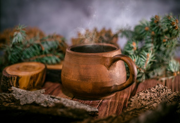 Pot of hot herbal tea, fir cones and paws of blue fir on wooden background