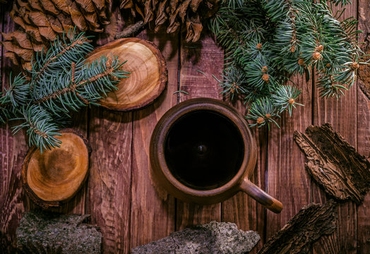 Pot of hot herbal tea, fir cones and paws of blue fir on wooden background