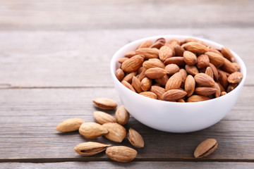 White bowl of almonds on grey background