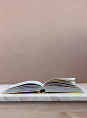 open book with yellow cover on table on brown background.