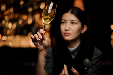 Female bartender looking at the cocktail with a sugar cube in the glass
