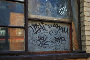 close up of a broken boarded up window and sill with peeling paint and graffiti