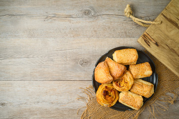 Burekas filled with cheese, potato and pizza rolls on wooden table.