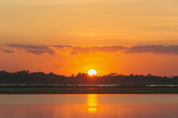 Naklejka premium Sunset in the lake. beautiful sunset behind the clouds above the over lake landscape background. dramatic sky with cloud at sunset