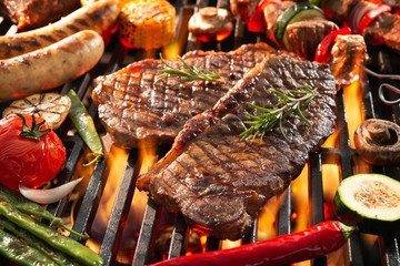 Delicious grilled meat with vegetables sizzling over the coals on barbecue - obrazy, fototapety, plakaty