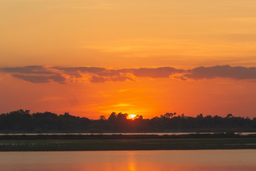 Naklejka premium Sunset in the lake. beautiful sunset behind the clouds above the over lake landscape background. dramatic sky with cloud at sunset