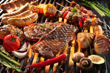 Delicious grilled meat with vegetables sizzling over the coals on barbecue - obrazy, fototapety, plakaty
