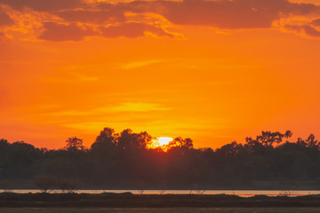 Sunset in the lake. beautiful sunset behind the clouds above the over lake landscape background. dramatic sky with cloud at sunset