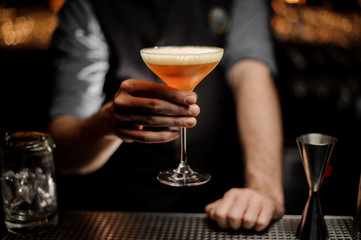 Male bartender serving cocktail with a whipped cream and grated nutmeg
