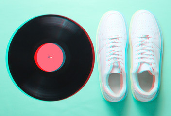 Pop culture. Glitch effect. White hipster sneakers, vinyl plate on mint-color background. Retro style. Top view, minimalism. .