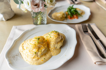 Egg Benedict on warm toast brioche. Two eggs delicious hollandaise sauce. Light morning Breakfast on table in restaurant.