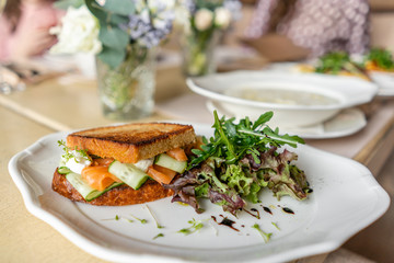 French toast brioche, Sandwich with salmon and cucumber. Light morning Breakfast, fresh warm pastries and aromatic cappuccino coffee on table in restaurant