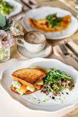 French toast brioche, Sandwich with salmon and cucumber. Light morning Breakfast, fresh warm pastries and aromatic cappuccino coffee on table in restaurant