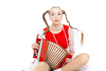 Pretty young sad woman  with ridiculous  plaits in russian folk costume plays an accordion at white...