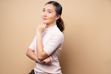 Obraz premium Happy woman thinking and standing isolated over beige brown background