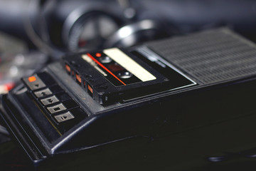 Old retro vintage black portable audio cassette player and recorder with audio tape on top 70s,...