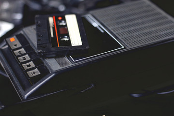 Old retro vintage black portable audio cassette player and recorder with audio tape on top 70s,...