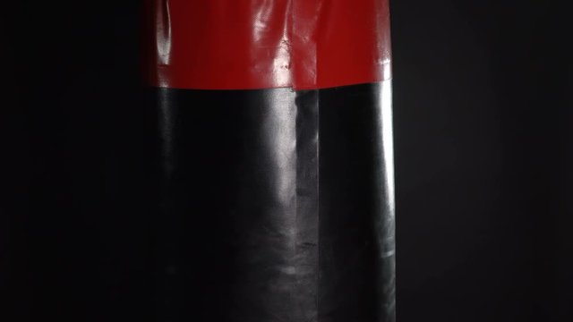 Punching bag in the gym on a black background