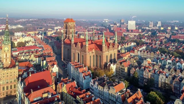 Gdansk, Poland. Old city with Gothic St. Mary church, city hall with clock tower, Dluga Street and old historic houses. Aerial revealing video in sunrise light