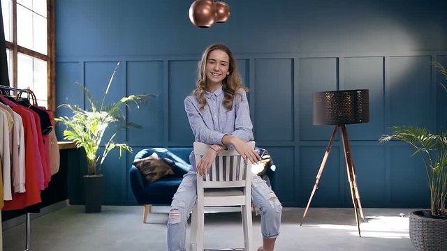 Attractive young woman sitting on the chair in the room at home.