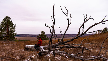 Fototapeta na wymiar A man sits on a fallen tree in the fall.