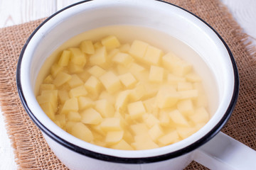 Peeled potatoes in a saucepan on a wooden table