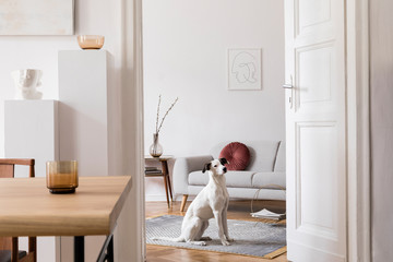 Stylish scandi interior of home space with design wooden table, chairs, sofa and accessories....