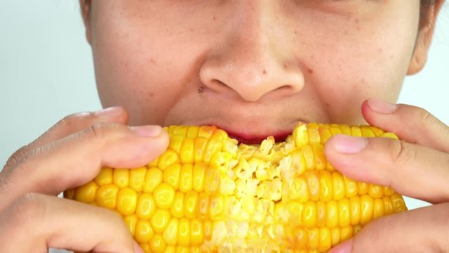 Close up mouth of Asian young woman eating boiled sweet corn, deliciously chewed with coughing and choking on white background.