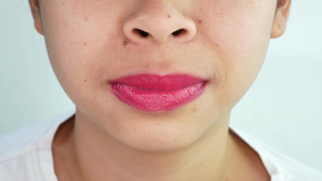Close up mouth of Asian young woman showing very quickly moves her tongue over white background in studio.