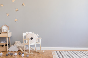 Stylish scandinavian newborn baby room with toys, children's chair, natural basket with teddy bear...
