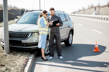 Woman with road assistance worker signing some documents standing near the car in road accident on the highway © rh2010