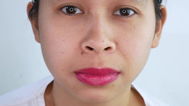 Close up face of Asian young woman expressive angry with pink painted lips over white background. Shot take in the studio.
