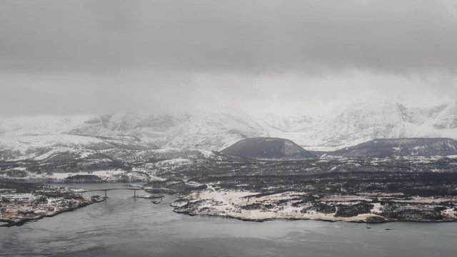 Bodo, Norway. Aerial view of Bodo, Norway in the cloudy morning. View of the famous northern fjord from above in winter with snow covered mountains. Grey landscape with cloudy sky