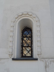 Figured window with bars on the white church wall