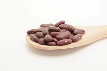 Alubia morada larga en una cuchara de madera sobre fondo blanco