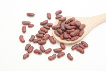 Alubia morada larga en una cuchara de madera sobre fondo blanco