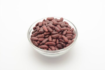 Alubia morada larga en un bol de cristal sobre fondo blanco