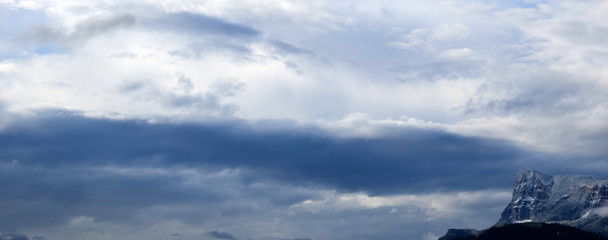 Fototapeta na wymiar Panorama - verschneite Berge und dunkle Regenwolken - Banner und Hintergrund
