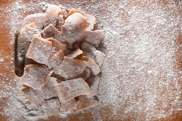 Photo of fruit candy from apples, sprinkled with powdered sugar and laid out on wooden boards
