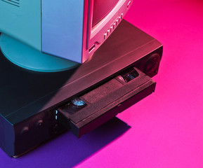 Retro wave, 80s concept. Video player with vhs cassette, old tv, neon light.